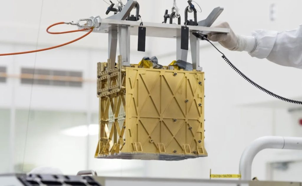 Техники из Лаборатории реактивного движения НАСА опускают инструмент эксперимента по использованию ресурсов кислорода на месте (MOXIE) Марса в брюхо марсохода Perseverance.
