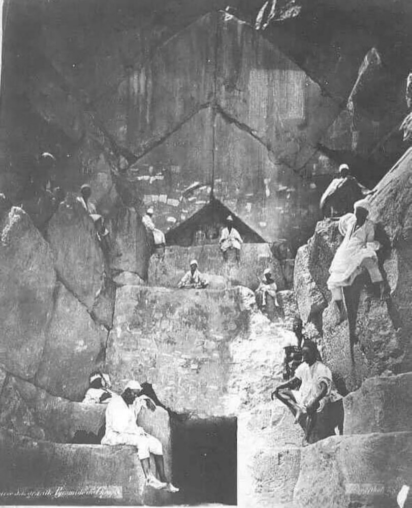 Люди стоят и сидят на массивных камнях, образующих вход в пирамиду. Кредит изображения: общественное достояние.